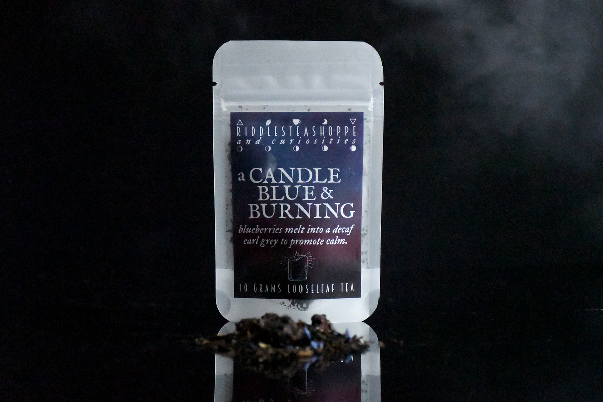 a Candle Blue & Burning Riddle's Tea Shoppe
